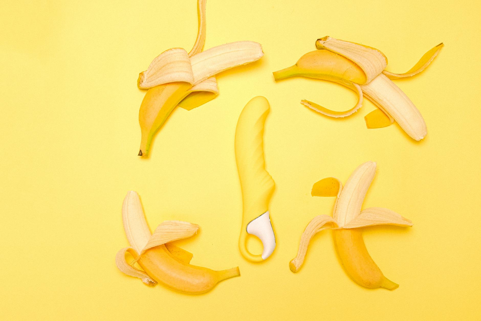 Yellow lemon vibrator arranged on a bright yellow background with fresh lemon slices
