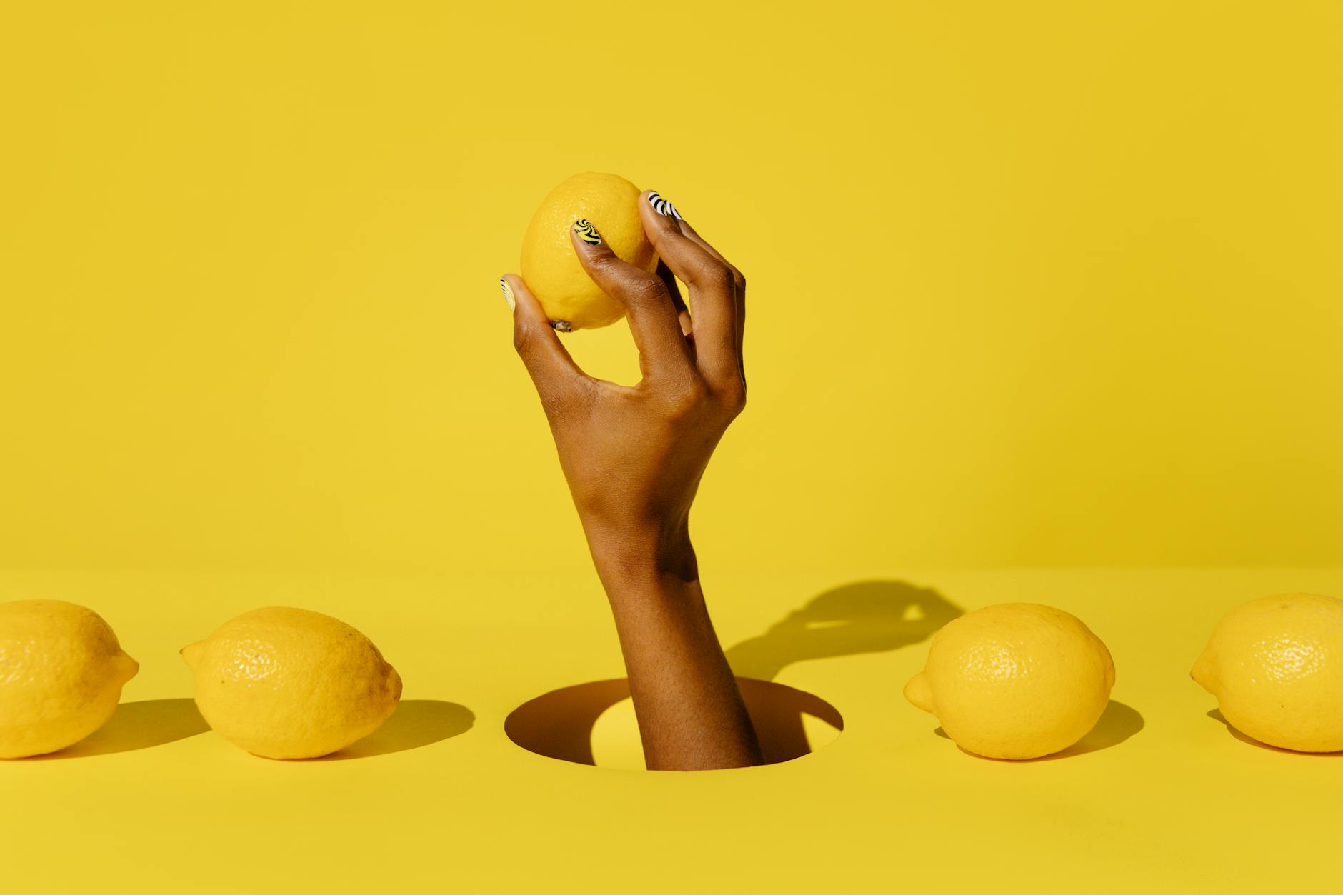 A hand holding a fresh lemon against a vivid yellow background, representing renewal and refreshed intimacy