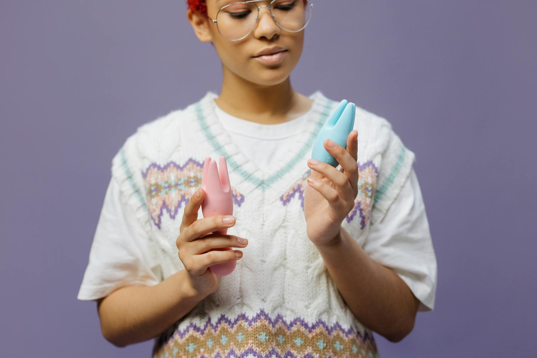 眼鏡をかけた女性が青とピンクのシリコンバイブレーターを持っている